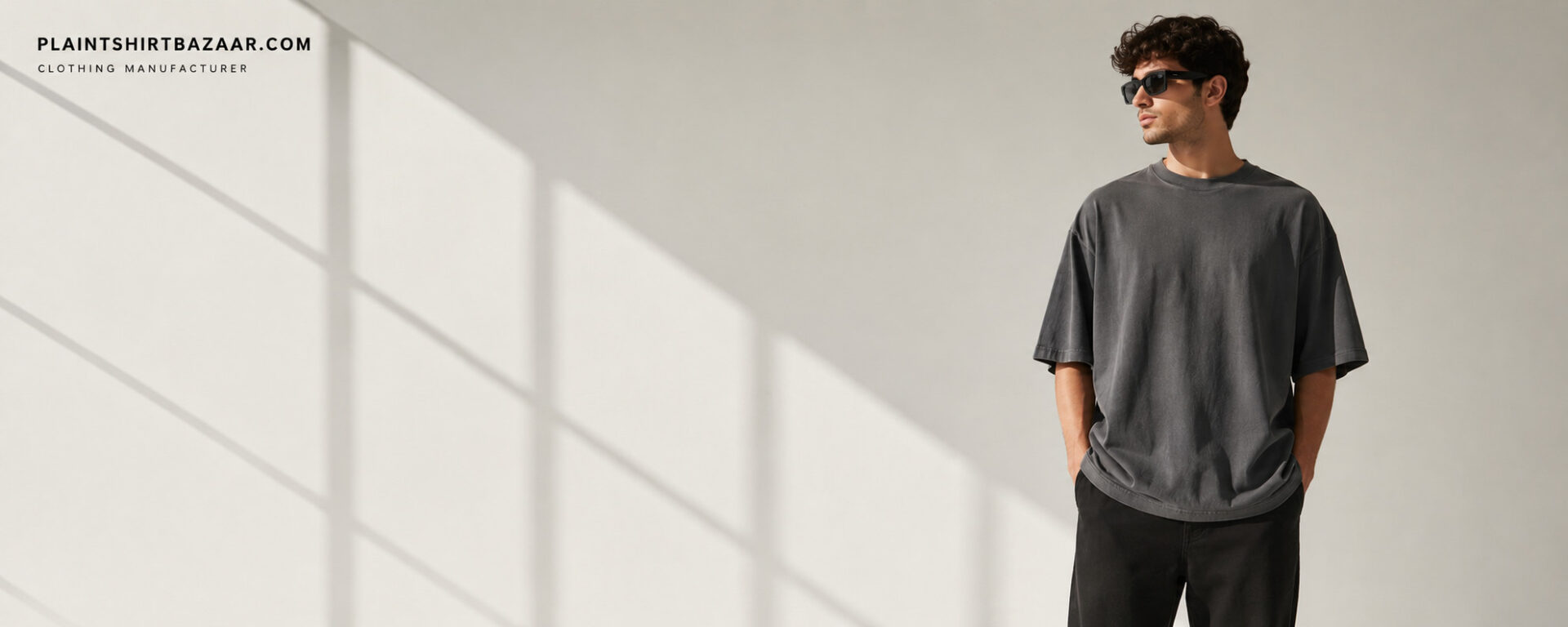 Male model wearing minimalist grey oversized t-shirt with sunglasses against neutral background